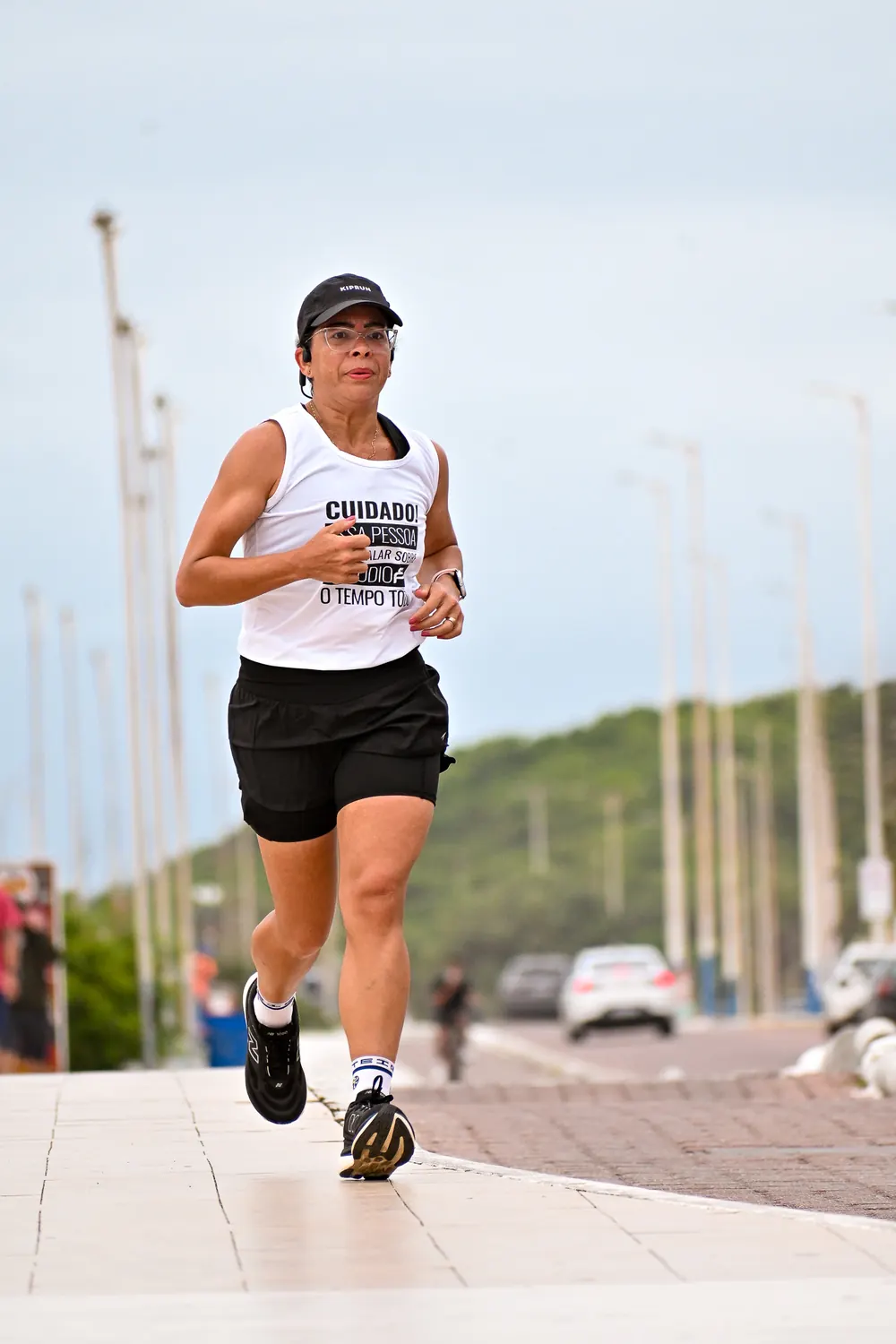 Corredora de boné e regata branca na ciclovia